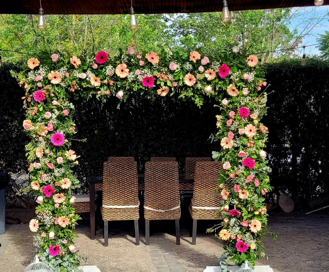 Arco cubierto de flores en fucsia, coral y durazno