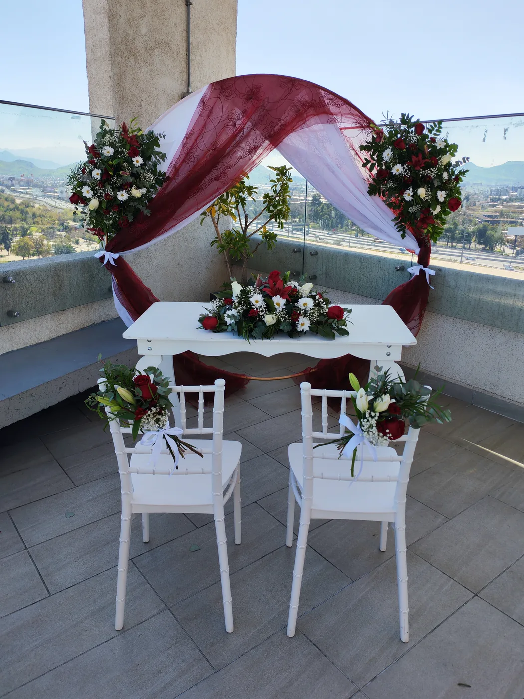 Arco cuadrado con rosas rojas y tul en terraza urbana
