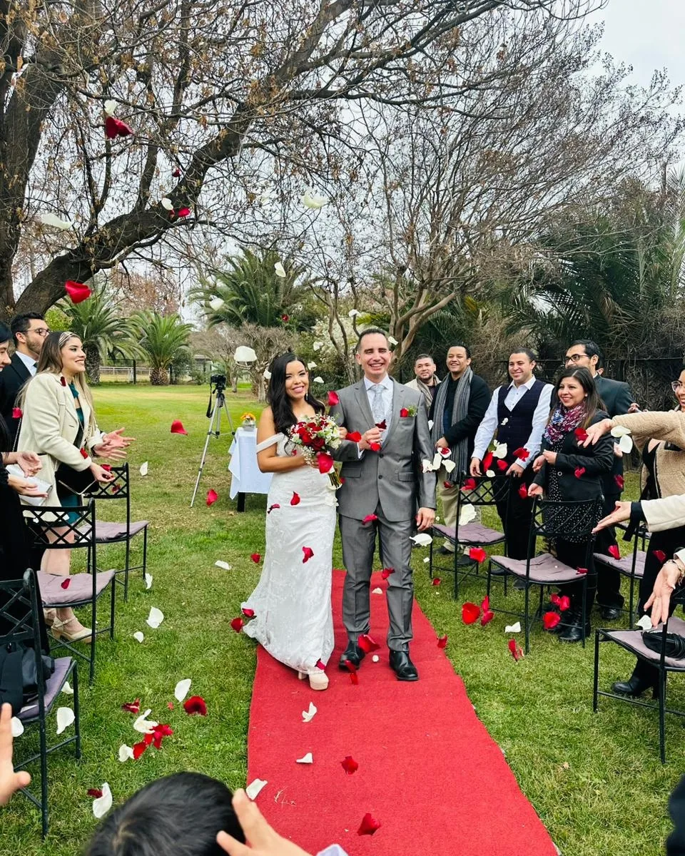 Los novios caminando por la alfombra mientras los invitados lanzan pétalos de rosa